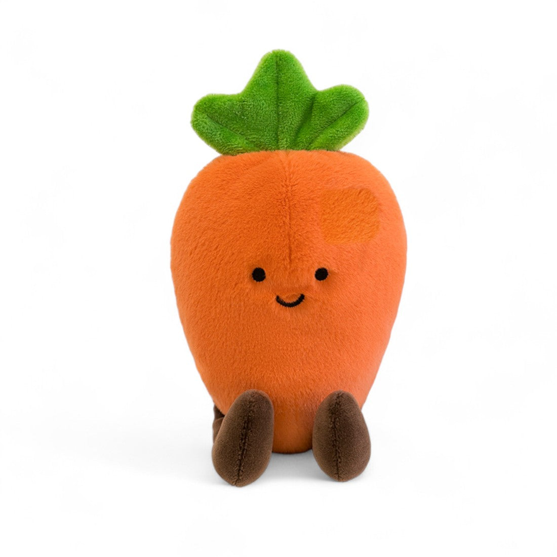 Peluche légume kawaii carotte joyeuse orange et verte, assise avec pattes marron vue de face sur fond blanc.