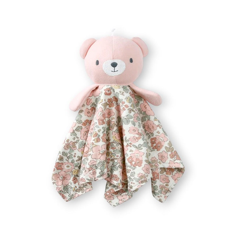 Doudou plat avec une tête d’ourson rose sur au dessus d'un carré en tissu fleuri en coton, sur fond blanc.