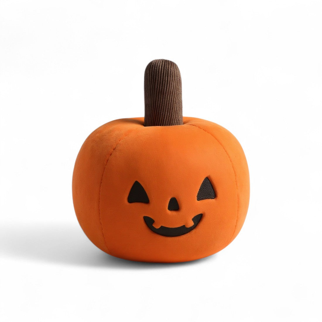 Peluche citrouille orange moelleuse avec sourire noir, sur fond blanc.