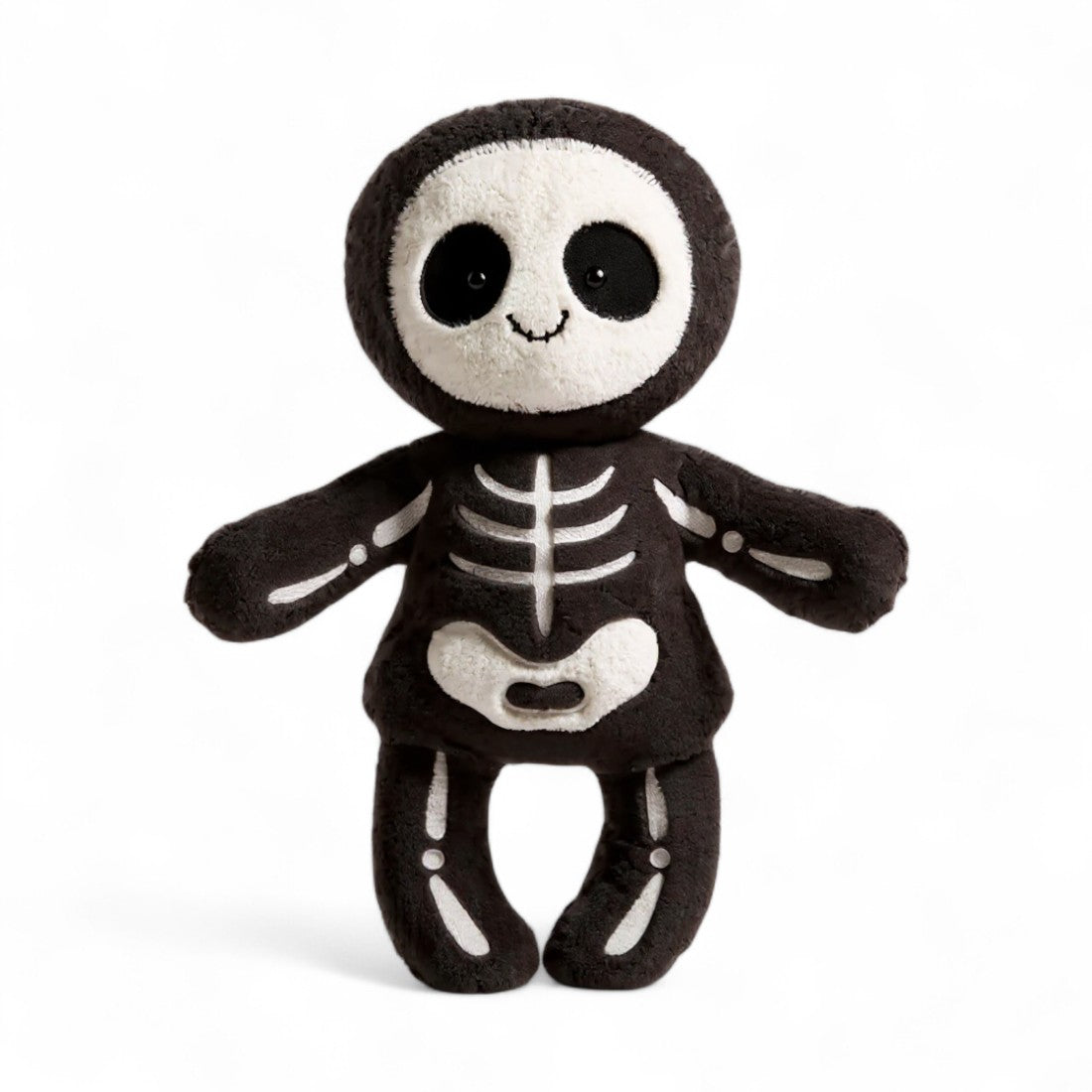 Peluche squelette noire et blanche au sourire doux, posée assise sur un plaid ou portée par un enfant.