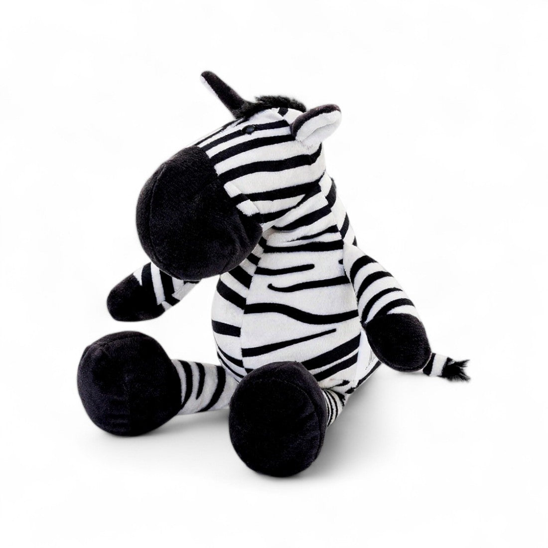 Peluche zèbre rayée noire et blanche, museau noir, grandes pattes et oreilles dressées, assis sur fond blanc.
