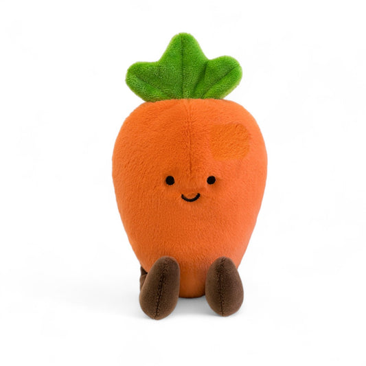 Peluche légume kawaii carotte joyeuse orange et verte, assise avec pattes marron vue de face sur fond blanc.