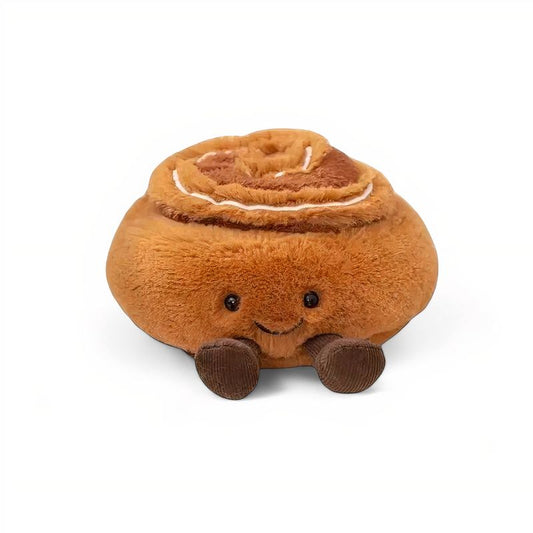 Peluche kawaii représentant un cinnamon roll souriant, avec des petites jambes brunes, posée sur une assiette blanche