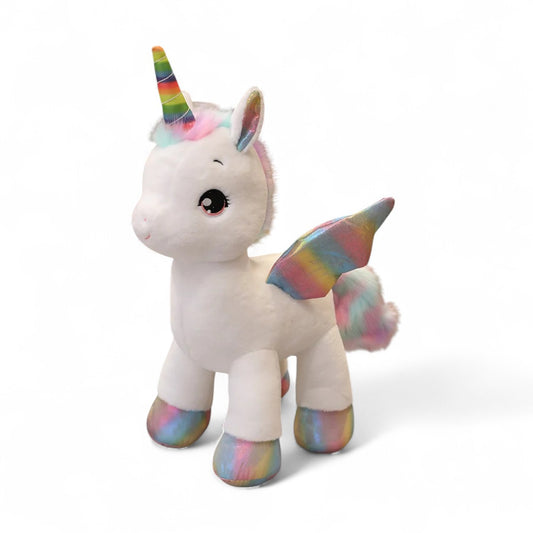 Peluche licorne blanche avec corne arc-en-ciel et ailes scintillantes, debout, sur fond blanc.
