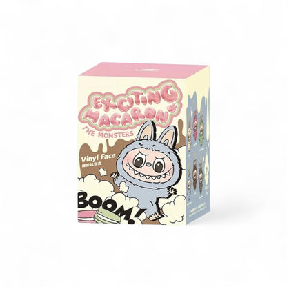 Boite en carton sur fond blanc, rose beige et grise, avec un dessin d'un monstre Labubu gris dessiné dessus, et des textes en anglais.