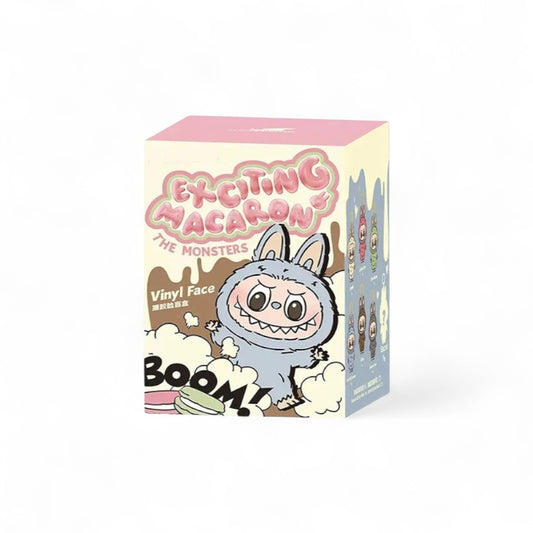 Boite en carton sur fond blanc, rose beige et grise, avec un dessin d'un monstre Labubu gris dessiné dessus, et des textes en anglais.