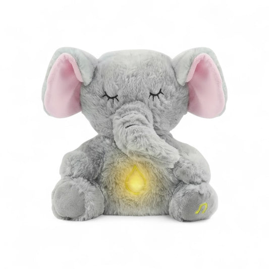 Peluche éléphant gris avec oreilles roses, yeux fermés et lumière douce au ventre, posée assise sur fond blanc