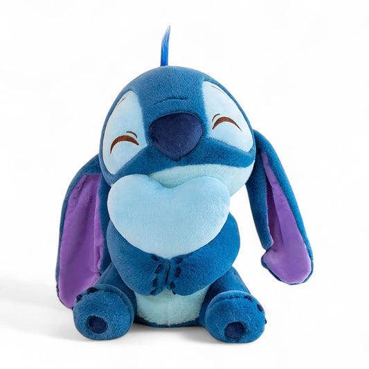 Peluche Disney Stitch tenant un cœur bleu, en peluche douce, sur fond blanc.