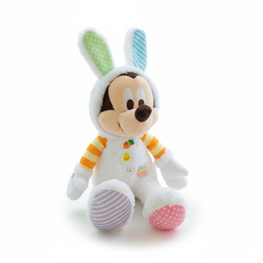 Peluche Mickey déguisé en lapin coloré de Pâques, oreilles vertes et bleues, pyjama blanc avec des broderies, assis sur fond blanc.