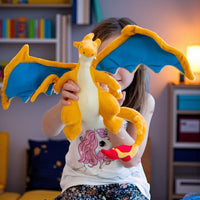 peluche pokémon - dracaufeu rugissant - tenue ailes déployées par une enfant