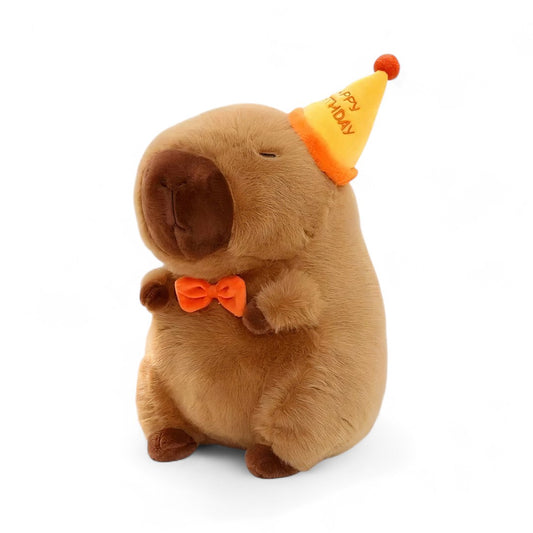 Peluche capybara marron avec chapeau de fête orange et nœud papillon, sur fond blanc.