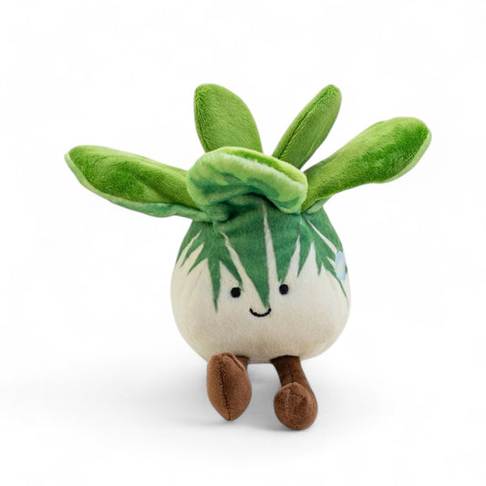 Peluche légume kawaii bok choy rigolo verte et blanche de 20 cm assise avec de longues pattes marron vue de face sur fond blanc.