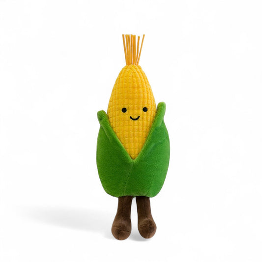 Peluche légume kawaii épi de maïs joyeux jaune et vert de 20 cm assise avec de longues pattes marron vue de face, sur fond blanc.