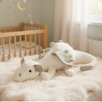 Dragon en peluche aux couleurs pastel - coloris blanc allongé sur un tapis blanc
