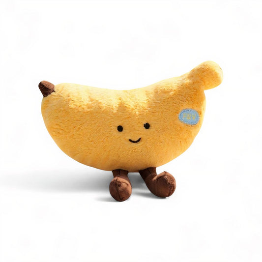 Peluche banane jaune au visage souriant, avec des pattes marron, posée sur fond blanc.
