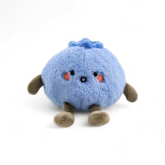 Petite peluche ronde bleue en forme de myrtille, avec des joues rosées, un sourire discret et des pattes marron, posée sur fond blanc.