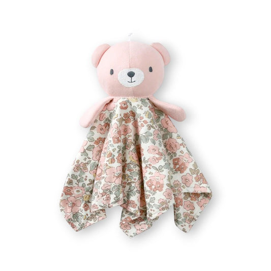 Doudou plat avec une tête d’ourson rose sur au dessus d'un carré en tissu fleuri en coton, sur fond blanc.