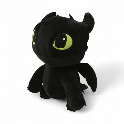 Peluche dragon noir, avec une grosse tête, et de grands yeux verts, sur fond blanc. 