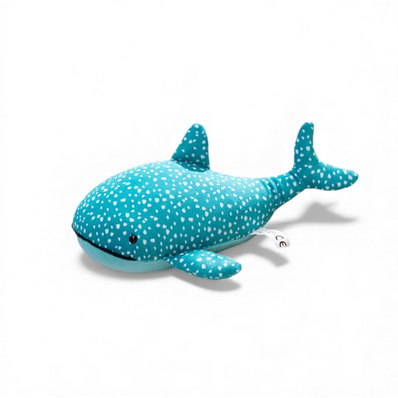 Peluche requin-baleine bleu turquoise d’environ 25 cm, couverte de petits pois blancs, avec nageoires et queue arrondies, ventre bleu clair uni et petit œil noir, posée seule sur fond blanc.