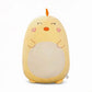Grand coussin peluche poussin jaune, 45 cm, ventre crème, yeux fermés, joues en forme de cœur et petit bec orange, posé sur un canapé clair.