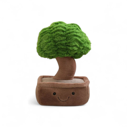 Peluche plante kawaii en forme de bonsaï souriant avec pot marron et feuillage vert, posée sur fond blanc.