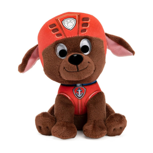 Peluche en forme de chiot Zuma marron de la Pat’ Patrouille, avec casque orange et large sourire, assise sur fond blanc.