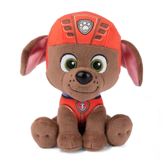 Peluche en forme de chiot Zuma marron de la Pat’ Patrouille, avec casque orange et large sourire, assise sur fond blanc.