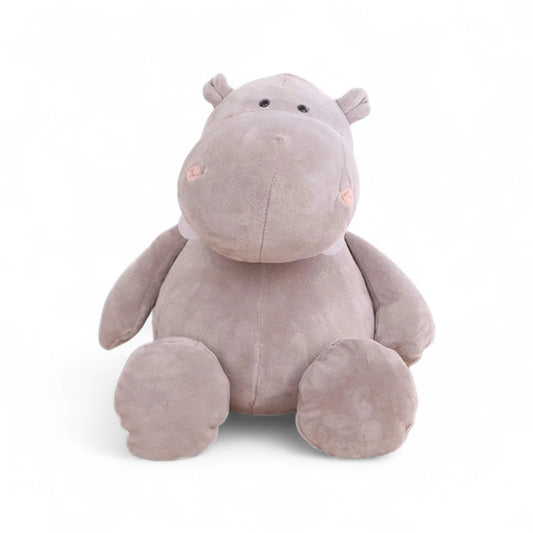 Hippopotame en peluche gris, au museau rond, grandes pattes et petites oreilles, posé avec un sourire doux sur fond blanc.