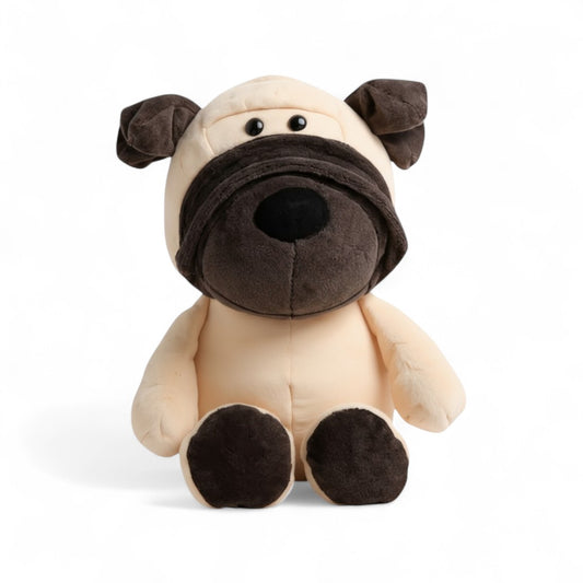 Peluche chien beige museau noir, oreilles tombantes, assis, regard malicieux et pattes arrondies sur fond blanc.