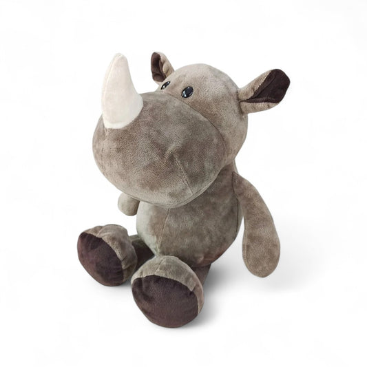 Rhinocéros en peluche gris, museau large, corne blanche moelleuse, assis sur fond blanc.