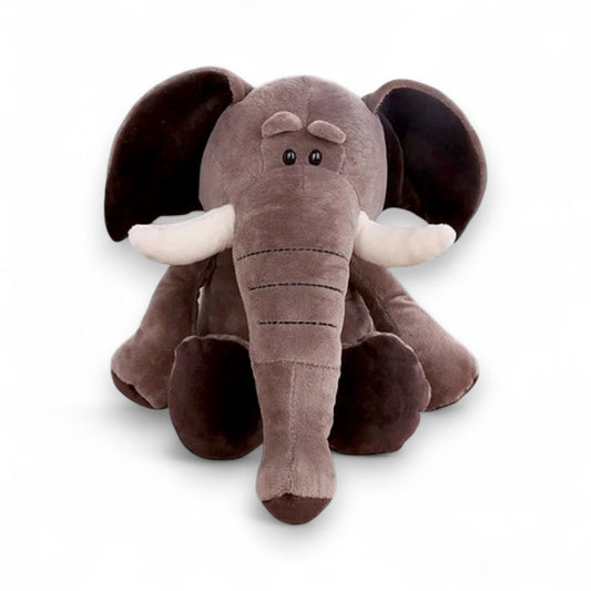 Peluche éléphant marron foncé, grandes oreilles, défenses blanches, trompe longue, assise sur fond blanc.