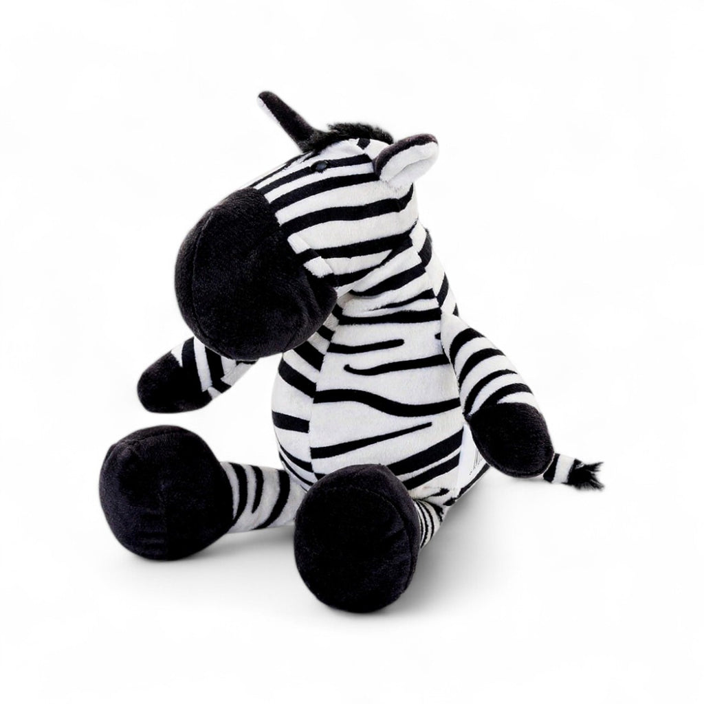 Peluche zèbre rayée noire et blanche, museau noir, grandes pattes et oreilles dressées,  assis sur fond blanc.