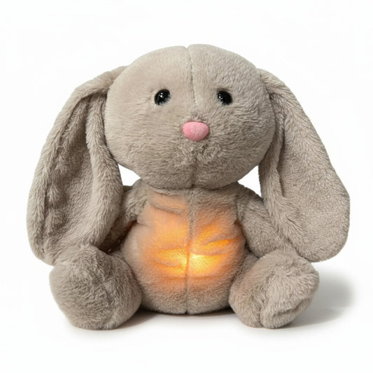  Lapin en peluche beige, ventre lumineux, oreilles tombantes, posé assis sur fond blanc.