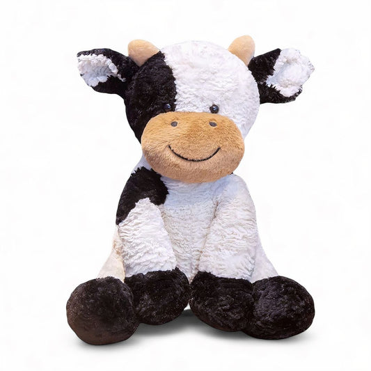 Vache en peluche noire et blanche, museau beige souriant, grandes oreilles, assise sur fond blanc.