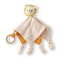 Doudou plat bébé lion crocheté, lange coton double gaze bicolore beige et orange, extrémités nouées et anneau bois naturel, fond blanc.