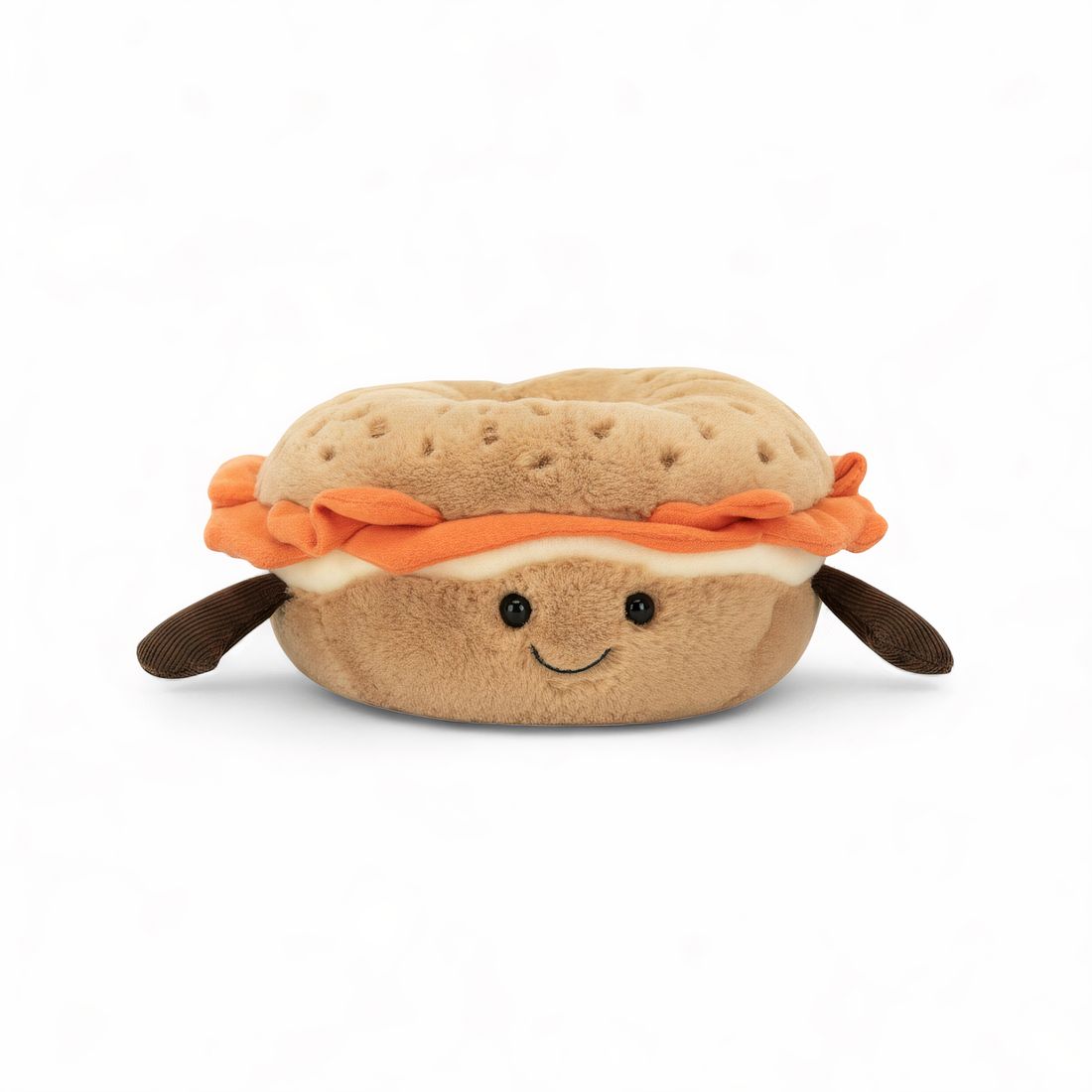 Peluche bagel beige avec graines, garni d'une tranche orange façon saumon, deux bras marron et un visage souriant, posée sur fond blanc