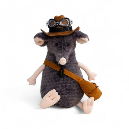 Peluche souris grise avec un chapeau marron et des lunettes noires, museau rond, grandes oreilles et longue queue claire, avec une sacoche en bandoulière, assise sur fond blanc