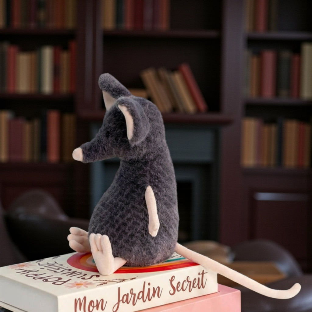 Peluche souris grise exploratrice - de dos, sur une pile de livres