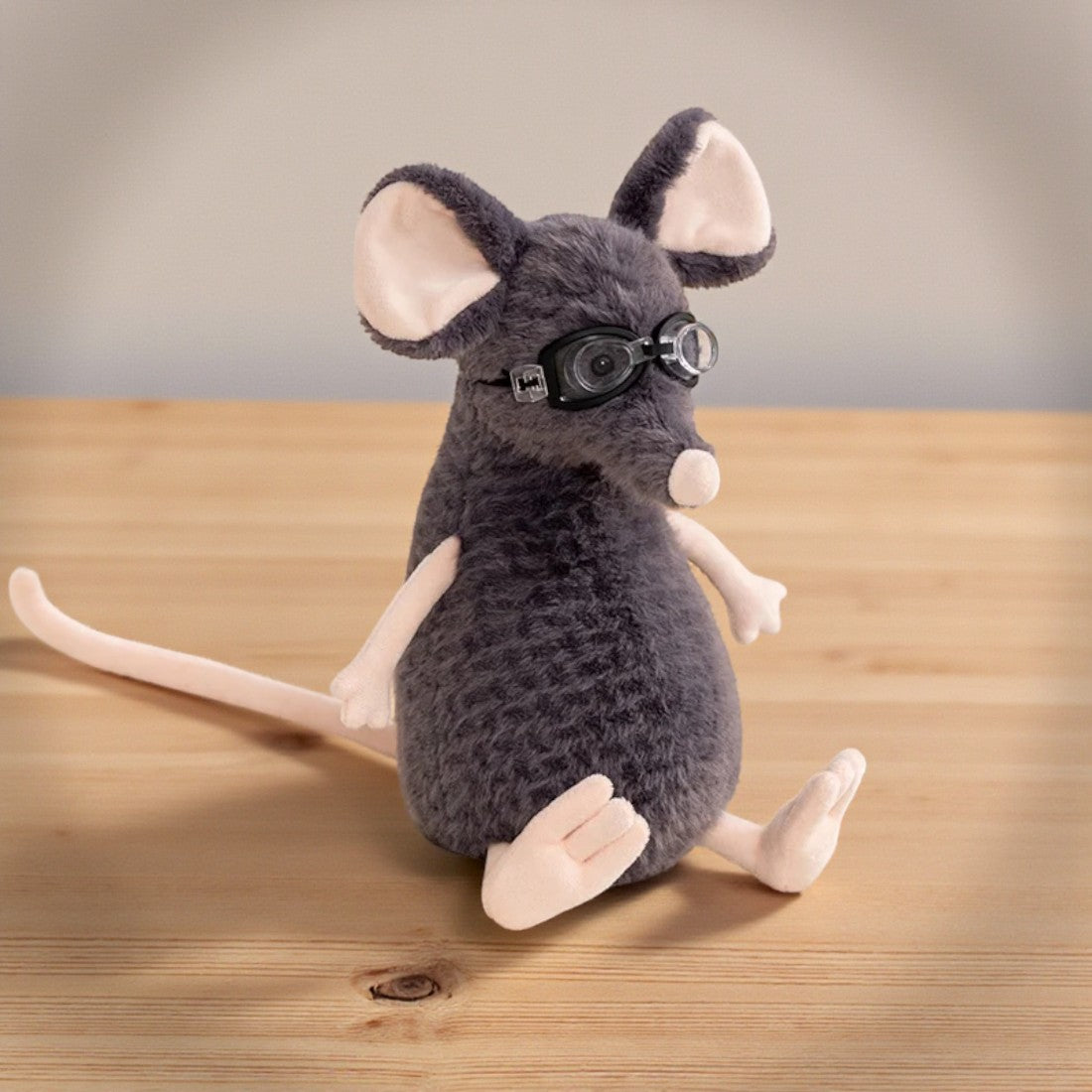 Peluche souris grise exploratrice - avec lunettes sur une table en bois