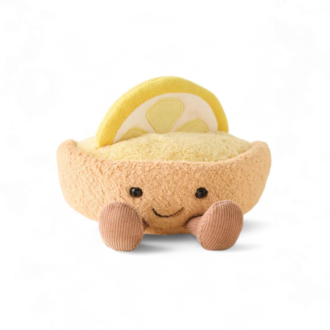 Peluche en forme de tarte jaune et beige, décorée d’une rondelle de citron et de deux jambes marron, sourire brodé, posée sur fond blanc