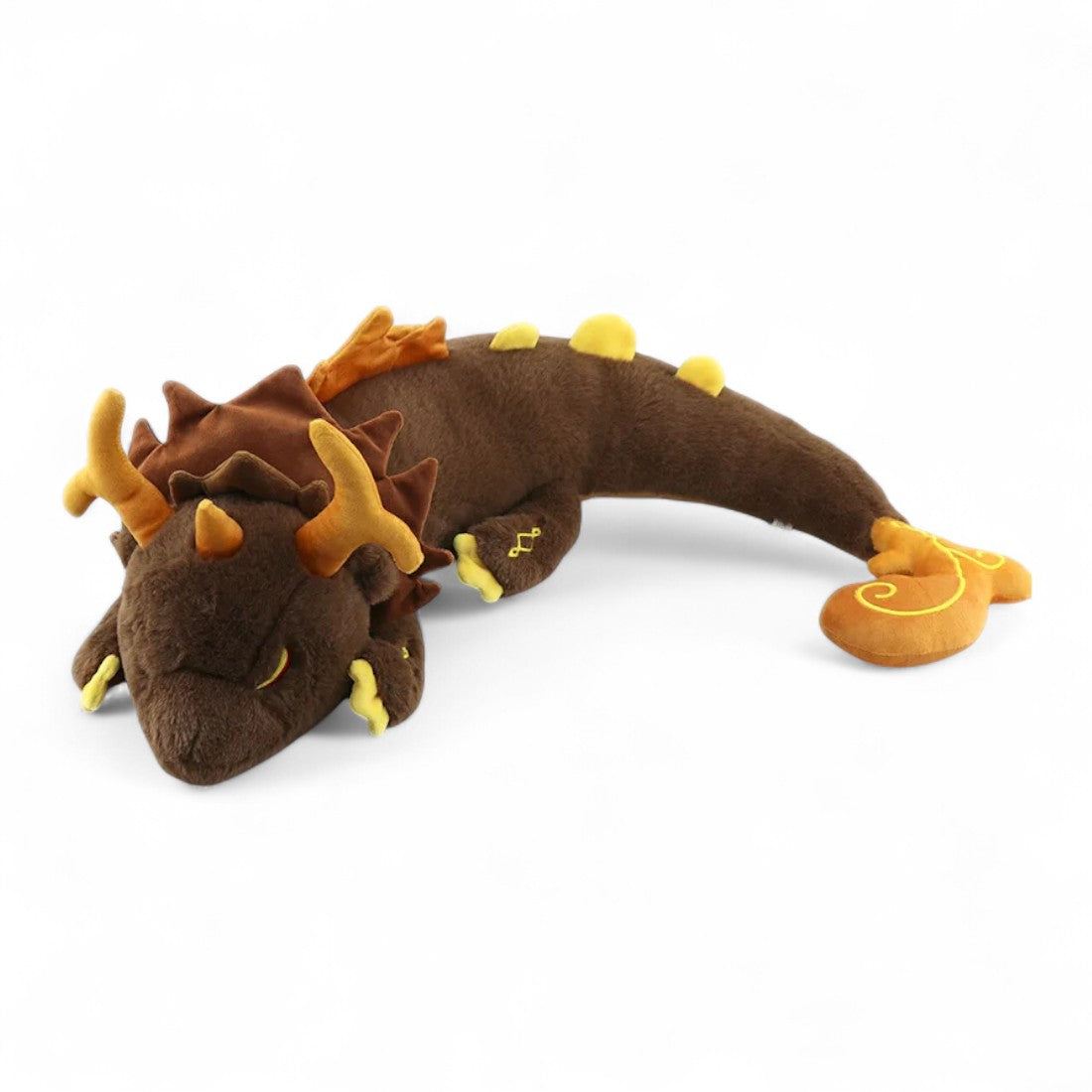 Grand dragon en peluche marron, allongé sur le ventre, cornes dorées, nageoires orange, détails jaunes sur pattes et queue, texture douce et aspect mythique sur fond blanc.