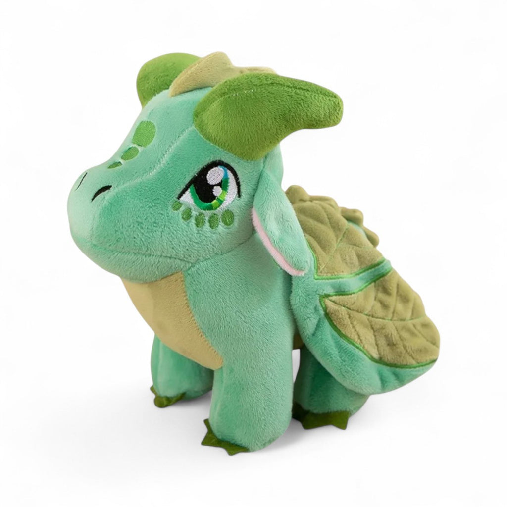 Petite peluche dragon vert tendre au ventre clair, grandes ailes en forme de feuilles, yeux expressifs, cornes vertes, sur fond blanc.