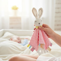 Doudou carré lapin minky pastel avec anneau de dentition - modèle rose tenu à la main