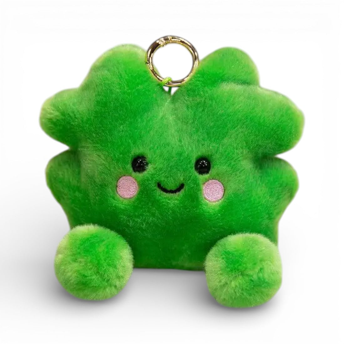 Peluche kawaii en forme de trèfle à quatre feuilles vert vif, grands yeux noirs brillants, joues roses rondes, sourire attendrissant, multiples feuilles duveteuses, deux petites pattes vertes potelées en bas, anneau doré sur le dessus, sur fond blanc.