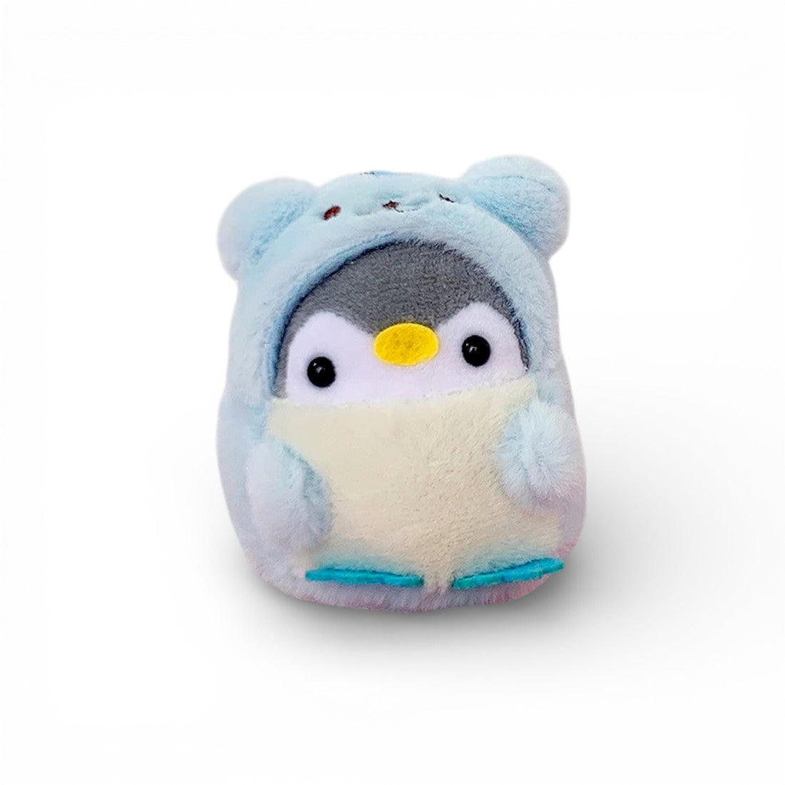 Un petit pingouin bleu duveteux déguisé en ourson, yeux ronds noirs brillants, bec jaune en feutrine, ventre beige, pattes bleues, sur fond blanc uni.
