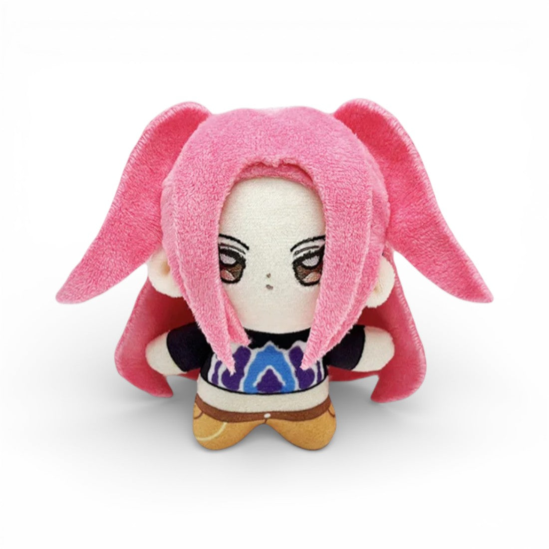 Peluche petite fille avec des cheveux roses longs, avec de grands yeux rouges ambrés brodés,habillée avec un tshirt noir violet et bleu et un pantalon orange, sur fond blanc.