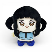 Peluche petite fille avec des cheveux noirs longs encadrant le visage, de grands yeux brillants brodés, habillée d'une tenue bleu foncé à motifs et pantalon bleu, sur fond blanc.