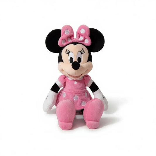 Peluche Minnie en robe rose à pois blancs avec grand nœud assorti sur la tête, assise, sur fond blanc.